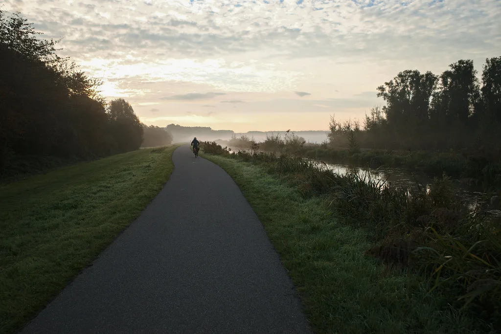 A cycle path beside a canal at dawn.