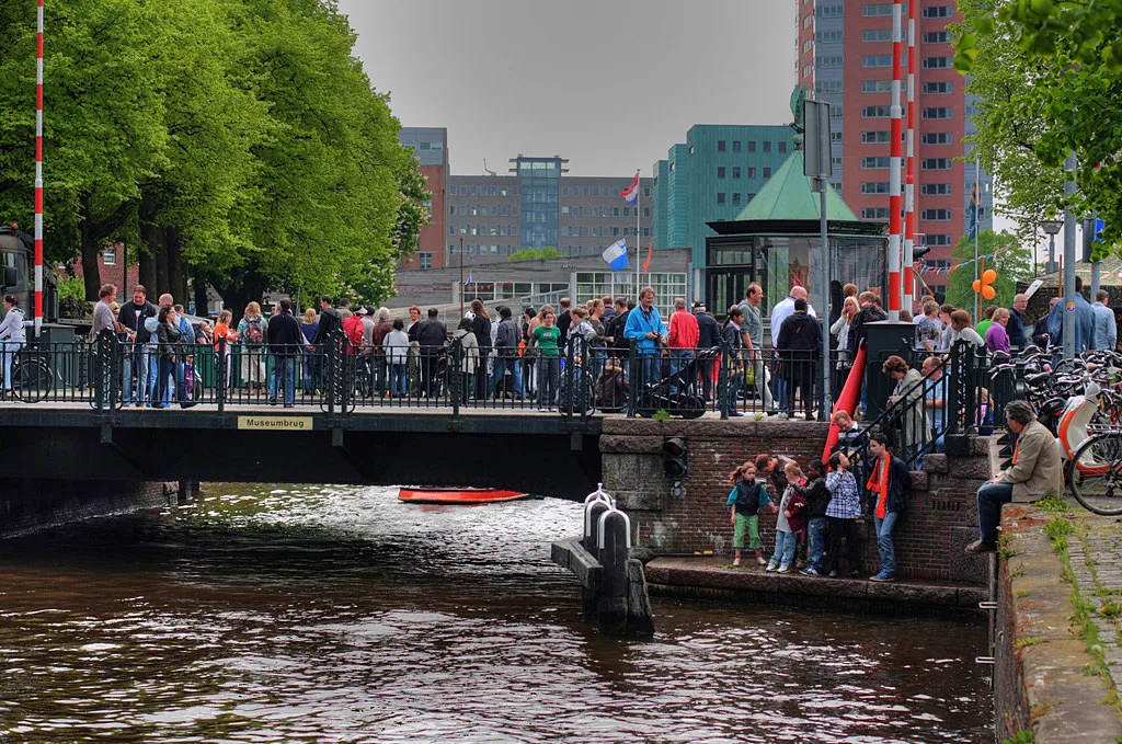 Crowds by a canal bridge on King's Day.