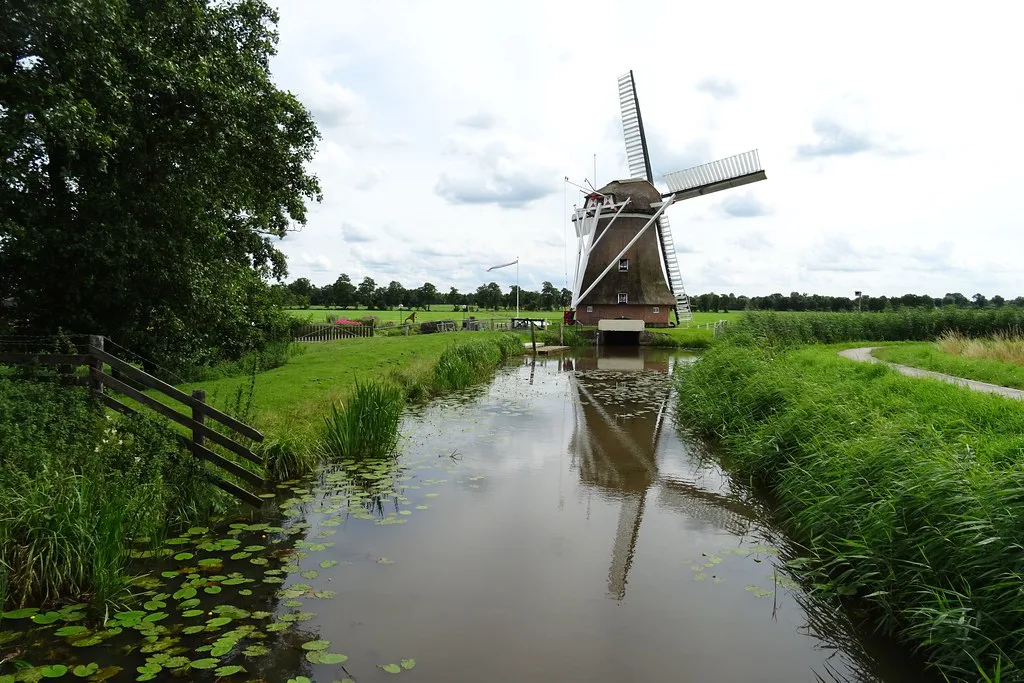 A windmill reflected in a polder canal.